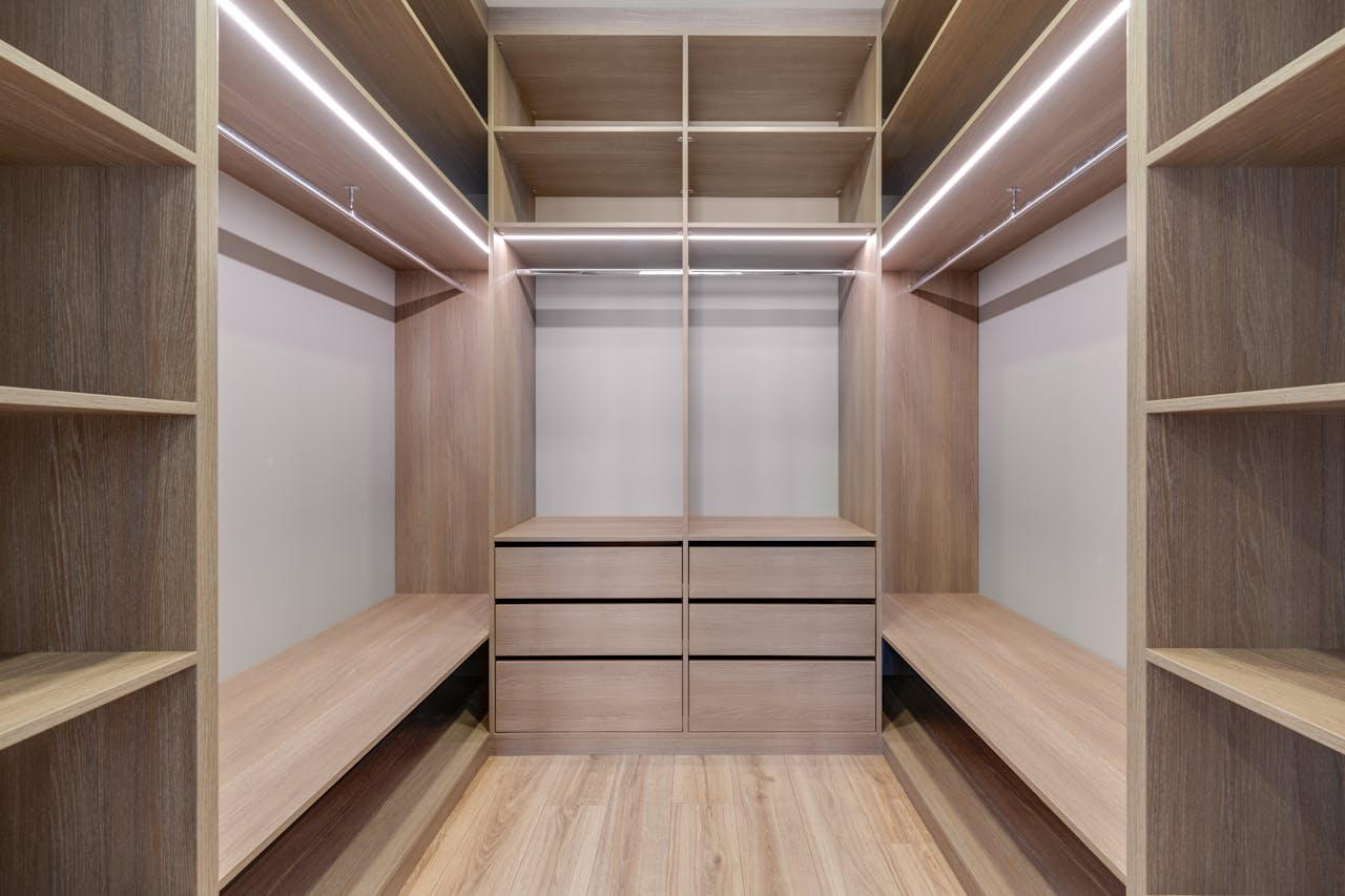 services-04 Spacious walk-in closet with wooden shelves and LED lighting creates a minimalist and modern design.