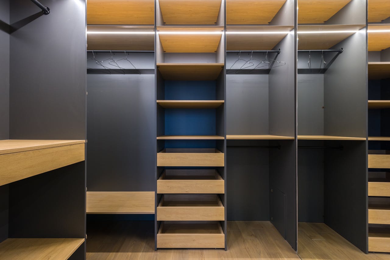 services-bg Spacious modern walk-in closet featuring wooden shelving and a sleek design, ideal for organization.