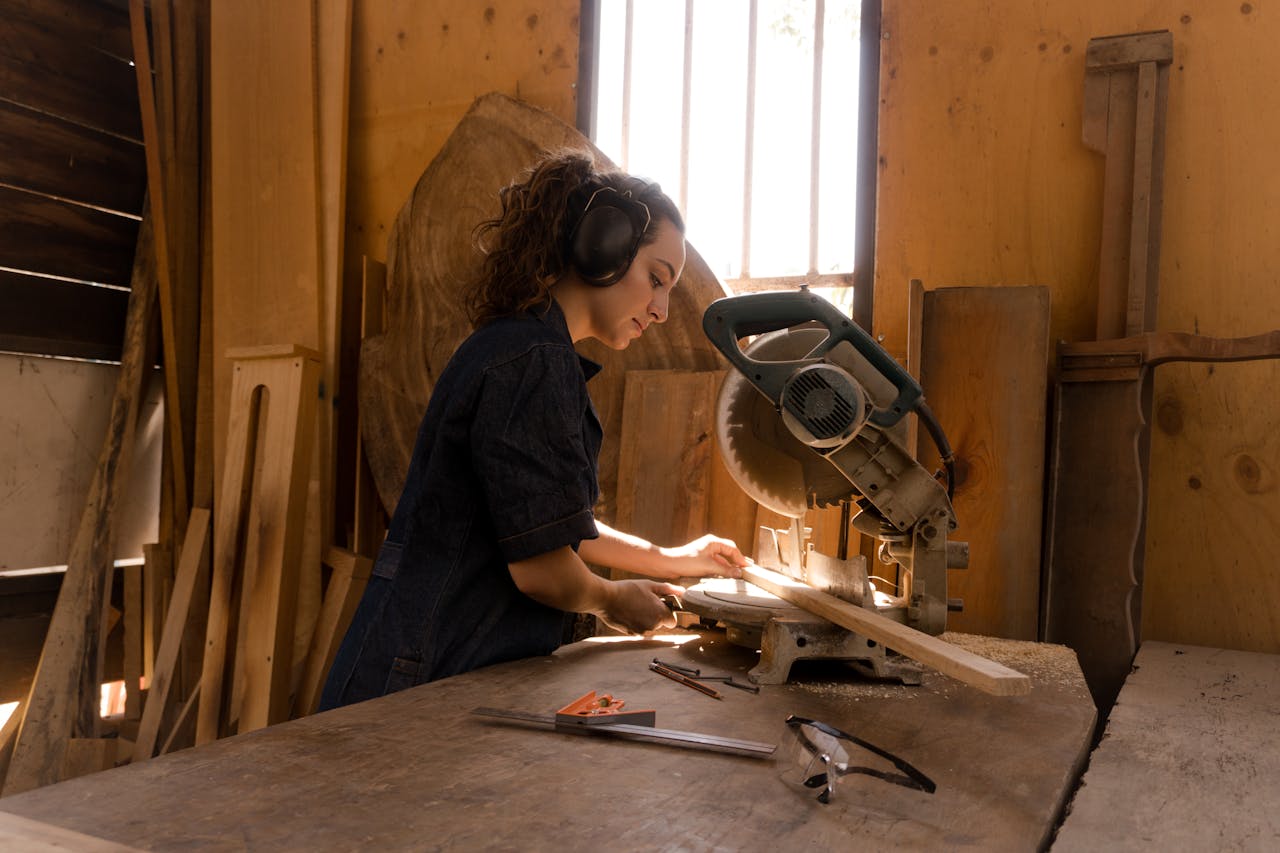 who-we-are Dedicated female carpenter using a circular saw in woodworking studio, focused on craftsmanship and precision.
